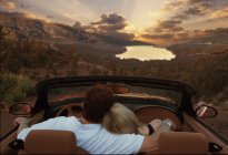 Couple sitting in convertible car looking at lake in Maldives woodland — Stock Photo