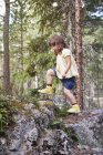Fille escalade sur les rochers dans la forêt — Photo de stock