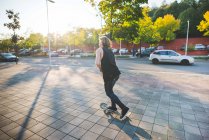 Jeune homme skateboard urbain skateboard le long du trottoir — Photo de stock