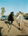 Donna cavallo a piedi sulla strada suburbana — Foto stock