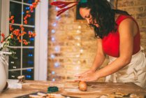 Mujer madura rodando pastelería de galletas de Navidad en el mostrador de cocina - foto de stock