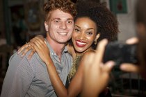Jovem casal tendo foto tirada no bar, sorrindo — Fotografia de Stock