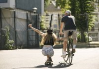 Вид ззаду на жіночого скейтбордера та велосипедиста на баскетбольному майданчику — стокове фото