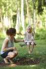 Mid adult mother and toddler daughter playing on garden swing — Stock Photo
