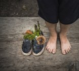 Piedi nudi di ragazzo accanto a scarpe piene di natura — Foto stock