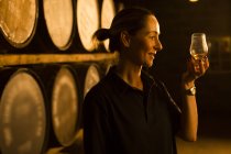 Женщина-дегустатор, глядя на цвет виски в стакане на заводе по производству виски — стоковое фото