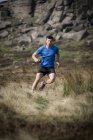 Corredor masculino correndo de Stanage Edge, Peak District, Derbyshire, Reino Unido — Fotografia de Stock
