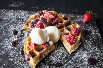 Strawberries and ice cream waffle on slate sprinkled with icing sugar — Stock Photo