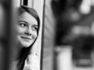 Усміхнена дівчина стоїть у дверному отворі, чорно-біла — стокове фото