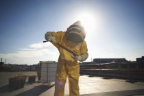 Пчеловод осматривает поднос с сотами на крыше города — стоковое фото