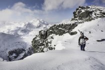 Esquiador masculino adulto medio caminando a lo largo de la cima de la montaña con esquís, Corvatsch, Suiza - foto de stock