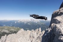 Wingsuit BASE jumper jumping from cliff, Italian Alps, Alleghe, Belluno, Italia - foto de stock