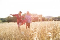 Молодая женщина с парнем танцует на пшеничном поле, Майорка, Испания — стоковое фото
