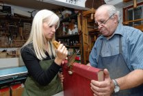 Senior man and young woman applying gold leaf to book spine in traditional bookbinding workshop — Stock Photo