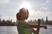 Woman by water stretching arm, Manhattan, New York, USA — Stock Photo