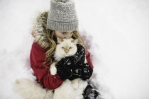 Portrait of green eyed white cat hugged by girl in snow — Stock Photo