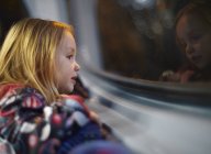 Menina olhando para fora de uma janela de ônibus durante uma viagem à noite — Fotografia de Stock