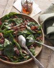 Spinach and bacon salad with spoon and fork in bowl — Stock Photo