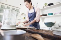 Jovem mulher moldando massa de farinha no balcão da cozinha — Fotografia de Stock