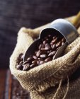 Кофейные зерна в тканом мешке с винтажным кофе совок — стоковое фото