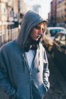 Man wearing hooded top and headphones, hands in pockets looking away — Stock Photo
