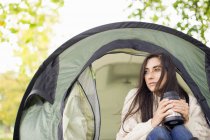 Молодая женщина в палатке держит фляжку — стоковое фото