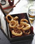 Коробка смажених кілець цибулі зі склянкою пива на столі — стокове фото