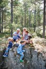 Семья сидит на скалах в лесу и ест пикник — стоковое фото