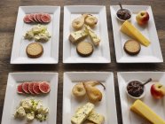 Assiettes avec différents fromages et fruits sur la table — Photo de stock