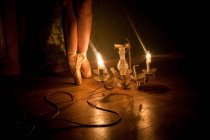 Feet of ballerina illuminated by chandelier light — Stock Photo