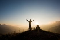 Вид сзади на человека на горной вершине с поднятыми руками, Пассо Фава, Италия — стоковое фото