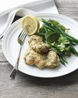 Plate of chicken with crusted chicken pieces, green beans, mesclun salad and lemon — Stock Photo