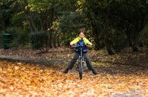 Хлопчик в парку їде на велосипеді восени — стокове фото
