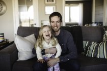 Портрет мужчины, сидящего на диване с дочерью на коленях — стоковое фото