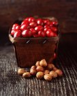 Cibo, punnet rustico pieno di mirtilli rossi e nocciole, tavolo in legno — Foto stock