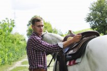 Porträt eines jungen Mannes beim Pferdesatteln — Stockfoto