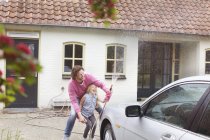 Mädchen hilft Vater beim Autowaschen vor Haus — Stockfoto