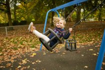 Fille balançant sur aire de jeux swing — Photo de stock