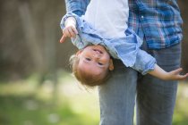 Low section of father hanging smiling baby boy upside down — Stock Photo