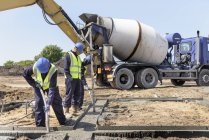 Apprentis constructeurs posant des fondations en béton sur le chantier — Photo de stock