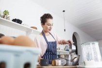Giovane donna che si prepara a cuocere al bancone della cucina — Foto stock