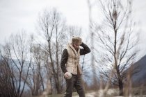 Mittlerer erwachsener Mann mit Trappermütze an Bäumen — Stockfoto
