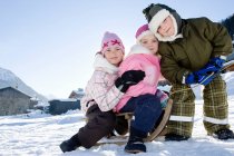 Niños jugando en la nieve con trineo - foto de stock