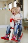Two preschooler sisters playing on rocking horse — Stock Photo