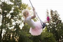 Baby girl swinging on park swing, rear view — Stock Photo