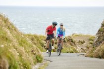 Велогонщики едут по дороге с видом на океан — стоковое фото