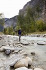 Мужчина-турист, переступающий породу в реке, Гриндельвальд, Швейцария — стоковое фото