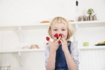 Retrato de linda chica con frambuesas en los dedos en la cocina - foto de stock