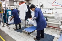 Працівники прасують сорочку на швейній фабриці — стокове фото