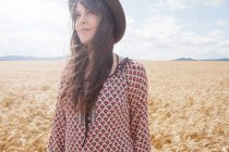 Взрослая женщина стоит на пшеничном поле — стоковое фото